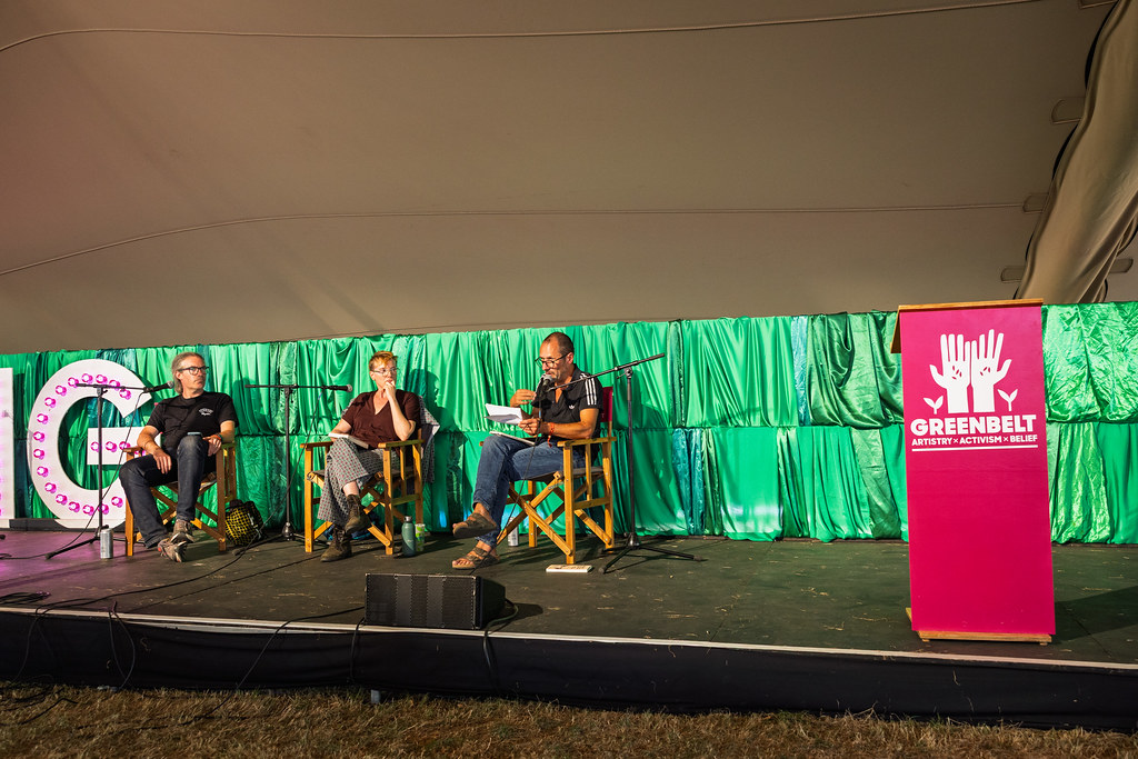 James, Hannah and Kester on stage in a tent with a Greenbelt banner - photo by Neil Mackin